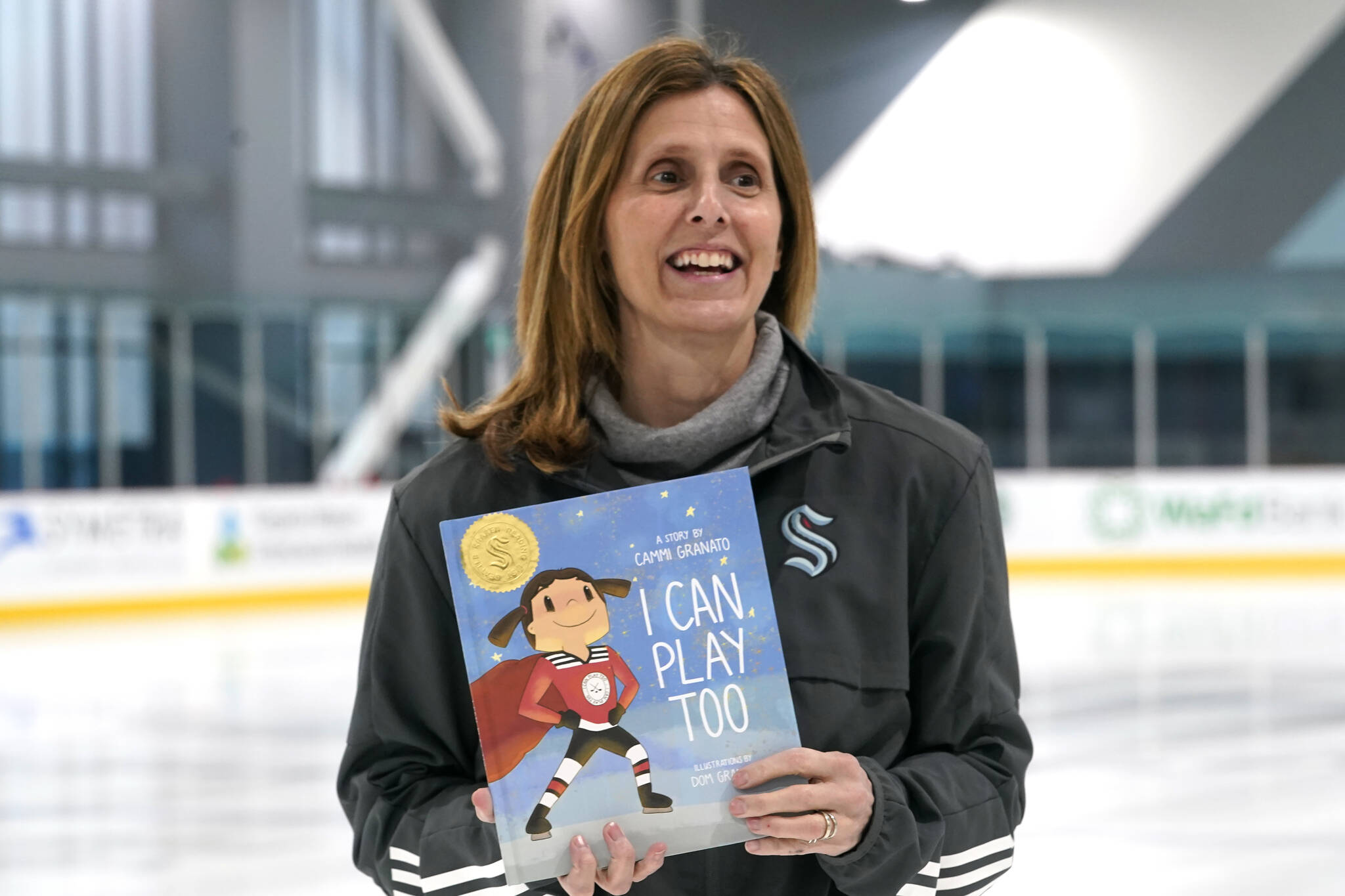 Cammi Granato poses with her new book, “I Can Play Too,” Wednesday, Feb. 2, 2022, in Seattle. For years, Hockey Hall of Famer Granato was asked to write a book about her experience in becoming one of the finest women’s hockey players of all time. She finally has, but on her own terms and with a specific audience in mind: kids. And while her book is based around hockey and her personal experiences, Granato is hoping the message can resonate beyond the ice. (AP Photo/Elaine Thompson)