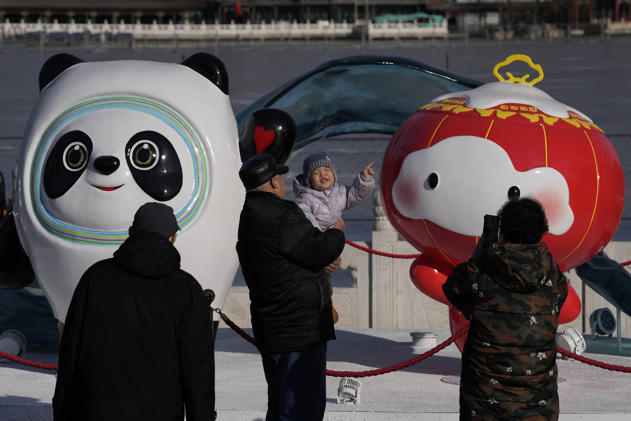 A child reacts near the Winter Olympics and Paralympics mascots, Bing Dwen Dwen, and Shuey Rhon Rhon along a lake in Beijing, China, Monday, Feb. 7, 2022. (AP Photo/Ng Han Guan)