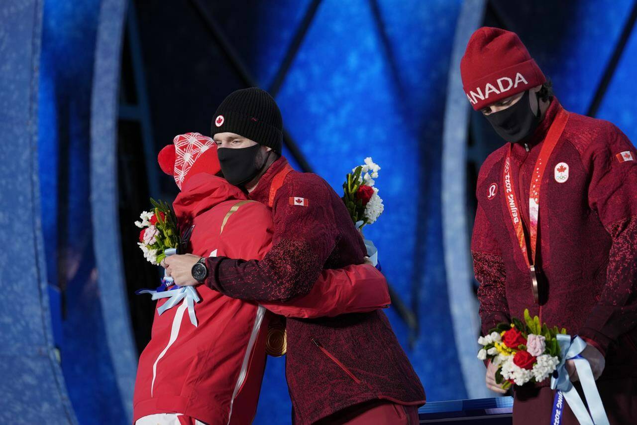 Silver medalist China’s Su Yiming, left, embraces gold medalist Canada’s Max Parrot during a medals ceremony for the men’s snowboard slopestyle event at the 2022 Winter Olympics, Monday, Feb. 7, 2022, in Zhangjiakou, China. (AP Photo/Aaron Favila)