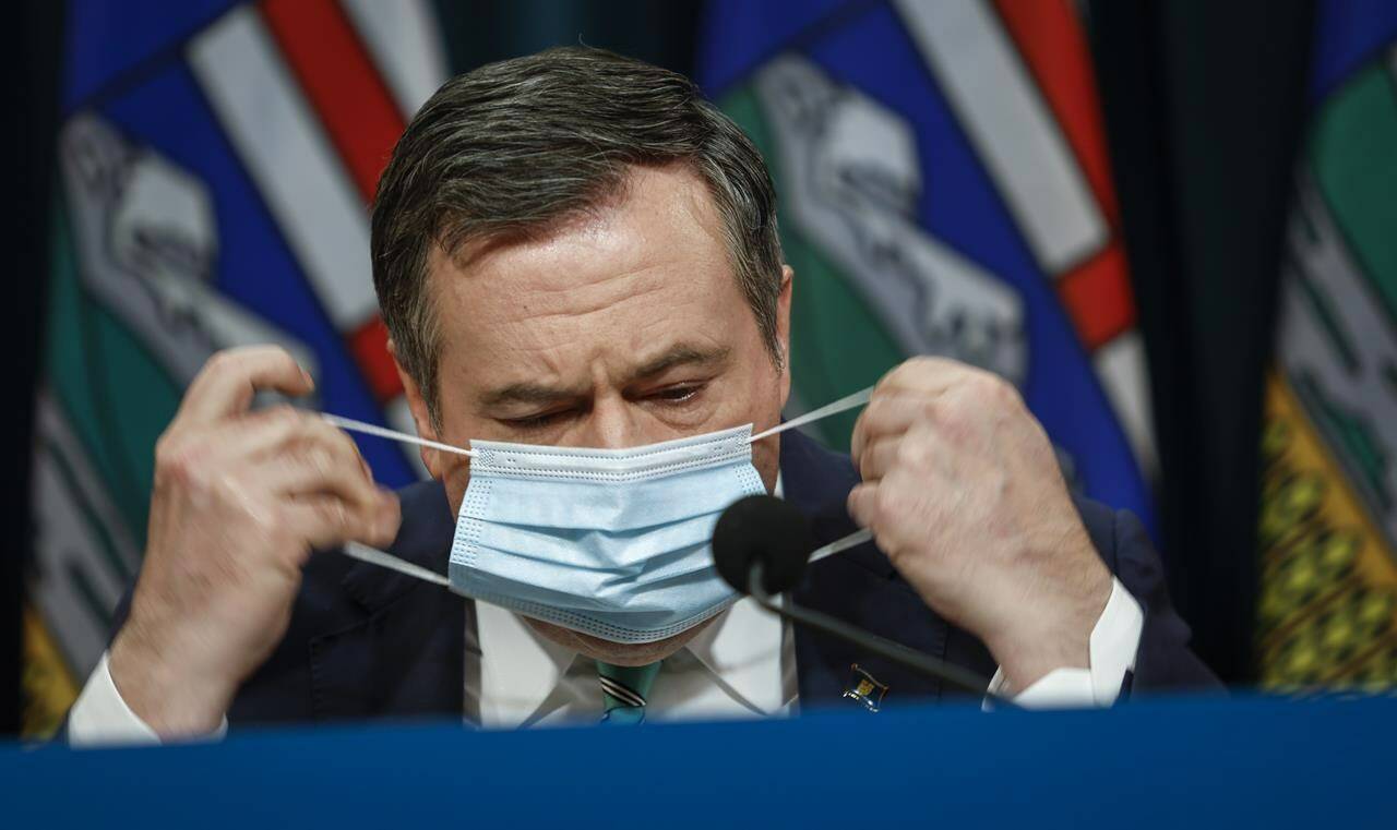 Alberta Premier Jason Kenney removes his mask as he gives a COVID-19 update in Calgary, Tuesday, Feb. 8, 2022. Faculty from the University of Alberta School of Public Health are voicing strong opposition to the rapid relaxation of COVID-19 health measures in the province, saying it could prolong the deadly pandemic. THE CANADIAN PRESS/Jeff McIntosh