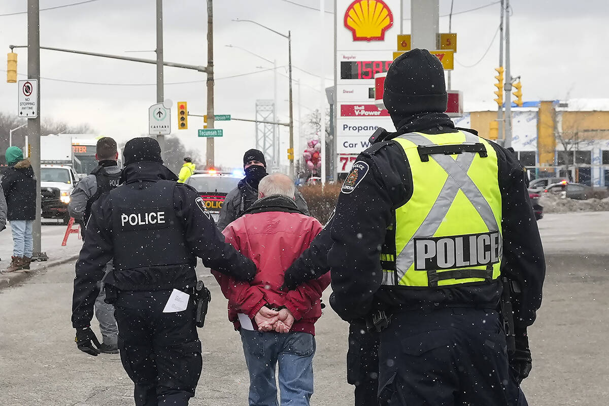 A protester is arrested by as police remove truckers and supporters after a court injunction gave police the power to enforce the law after blocking the access leading from the Ambassador Bridge, linking Detroit and Windsor, as truckers and their supporters continue to protest against the COVID-19 vaccine mandates and restrictions in Windsor, Ont., on Sunday, February 13, 2022. THE CANADIAN PRESS/Nathan Denette