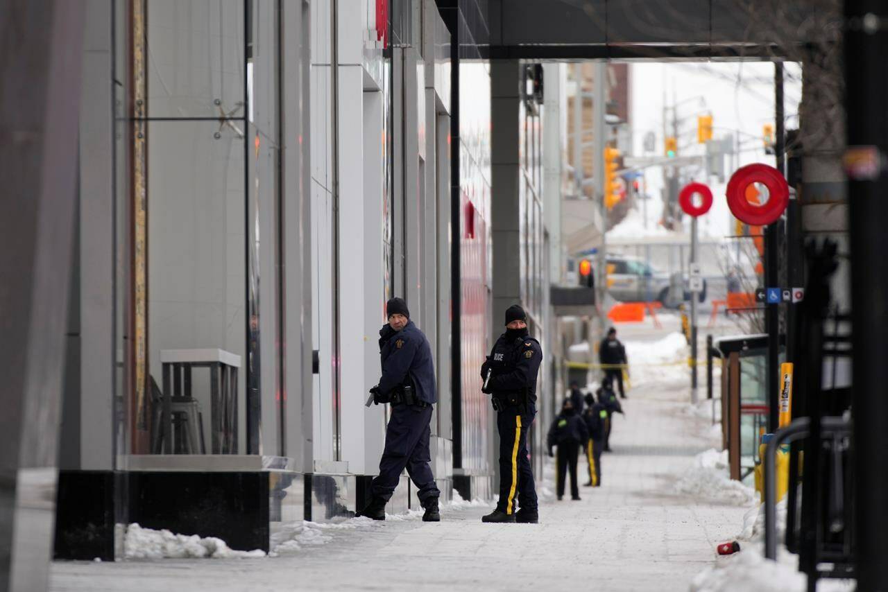 Police officers with their weapons drawn are shown outside the Rideau Centre in Ottawa on Tuesday, Feb. 22, 2022. Ottawa’s largest mall has been evacuated and a suspect has been arrested with a possible weapon, on the first day the mall has been open since protests forced stores to shut down late last month. THE CANADIAN PRESS/David Kawai