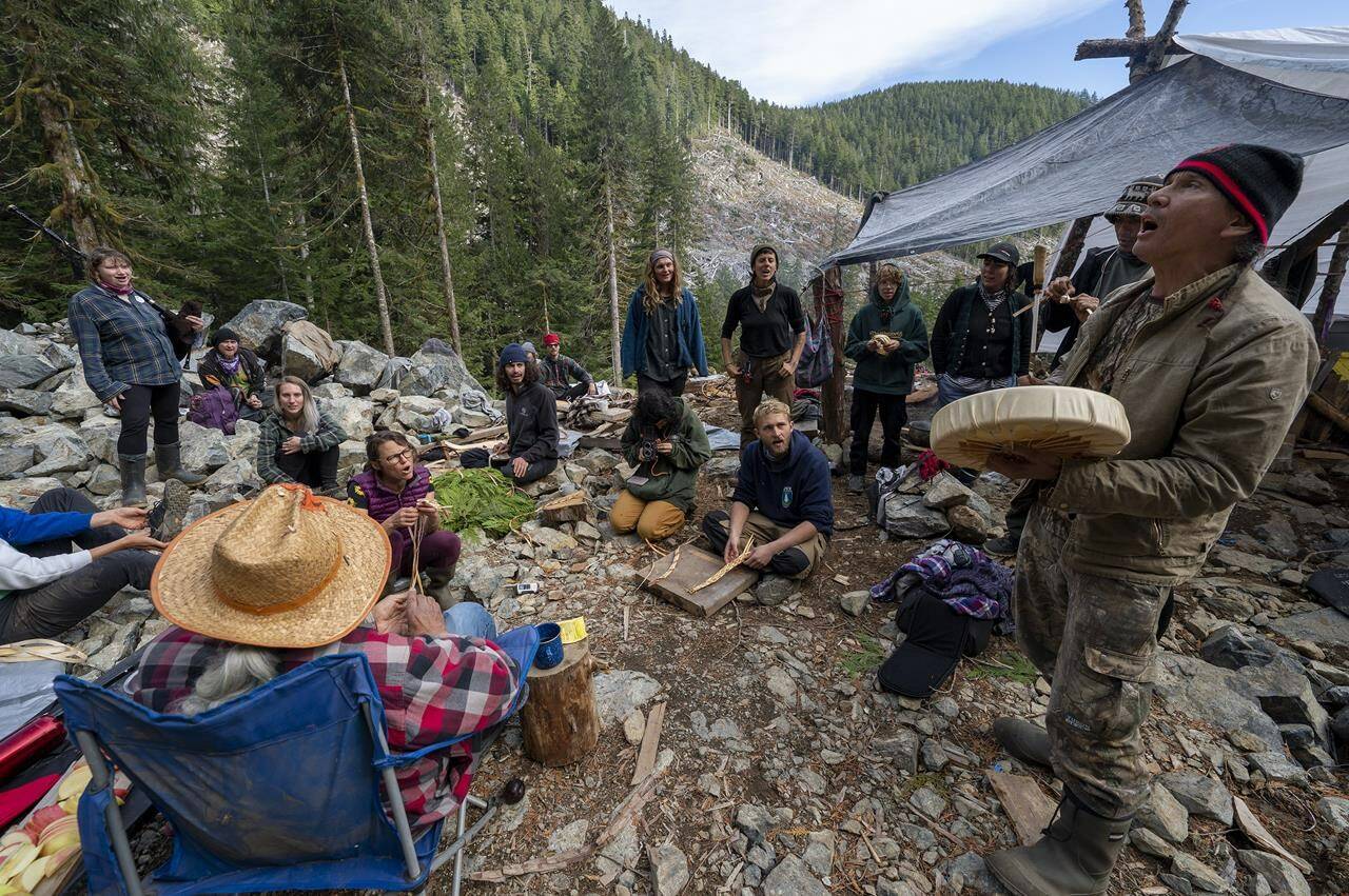 People who have declared themselves “Land Defenders” sing a song as they guard an area of a logging cut block called “Heli Camp” in the Fairy Creek logging area near Port Renfrew, B.C. Monday, Oct. 4, 2021. THE CANADIAN PRESS/Jonathan Hayward