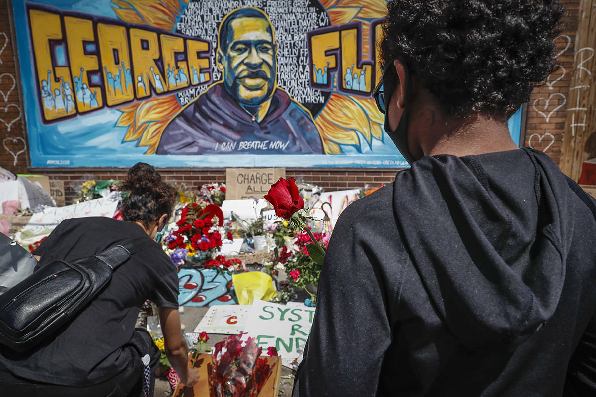 Mourners gather to place flowers at a makeshift memorial for George Floyd at the corner of Chicago Avenue and East 38th Street, Sunday, May 31, 2020, in Minneapolis. Protests continued following the death of Floyd, who died after being restrained by Minneapolis police officers on May 25. (AP Photo/John Minchillo)