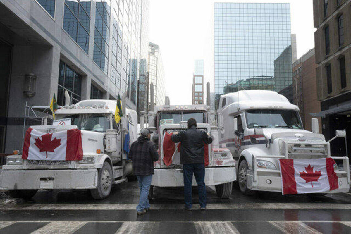 Truck drivers hang a Canadian flag on the front grille of a truck parked in downtown Ottawa near Parliament Hill on Feb. 2. (Adrian Wyld/Canadian Press)