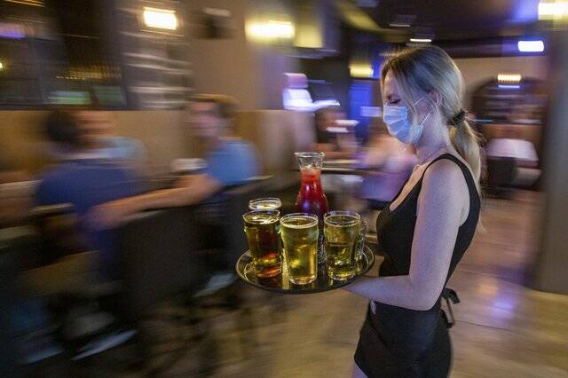 Waitress Kirsten Craig wears a mask while carrying drinks for guests inside the Blu Martini restaurant in Kingston, Ont., on July 16, 2021. THE CANADIAN PRESS/Lars Hagberg