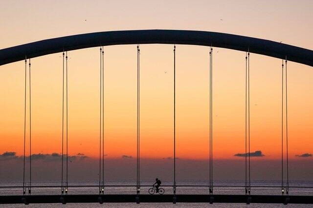 A cyclist crosses Humber Bay Arch Bridge during sunrise in Toronto on Friday, November 5, 2021. Canadians should be patient this spring as a “temperature rollercoaster” is expected across the country in the coming weeks, according to predictions from a prominent national forecaster.THE CANADIAN PRESS/Evan Buhler