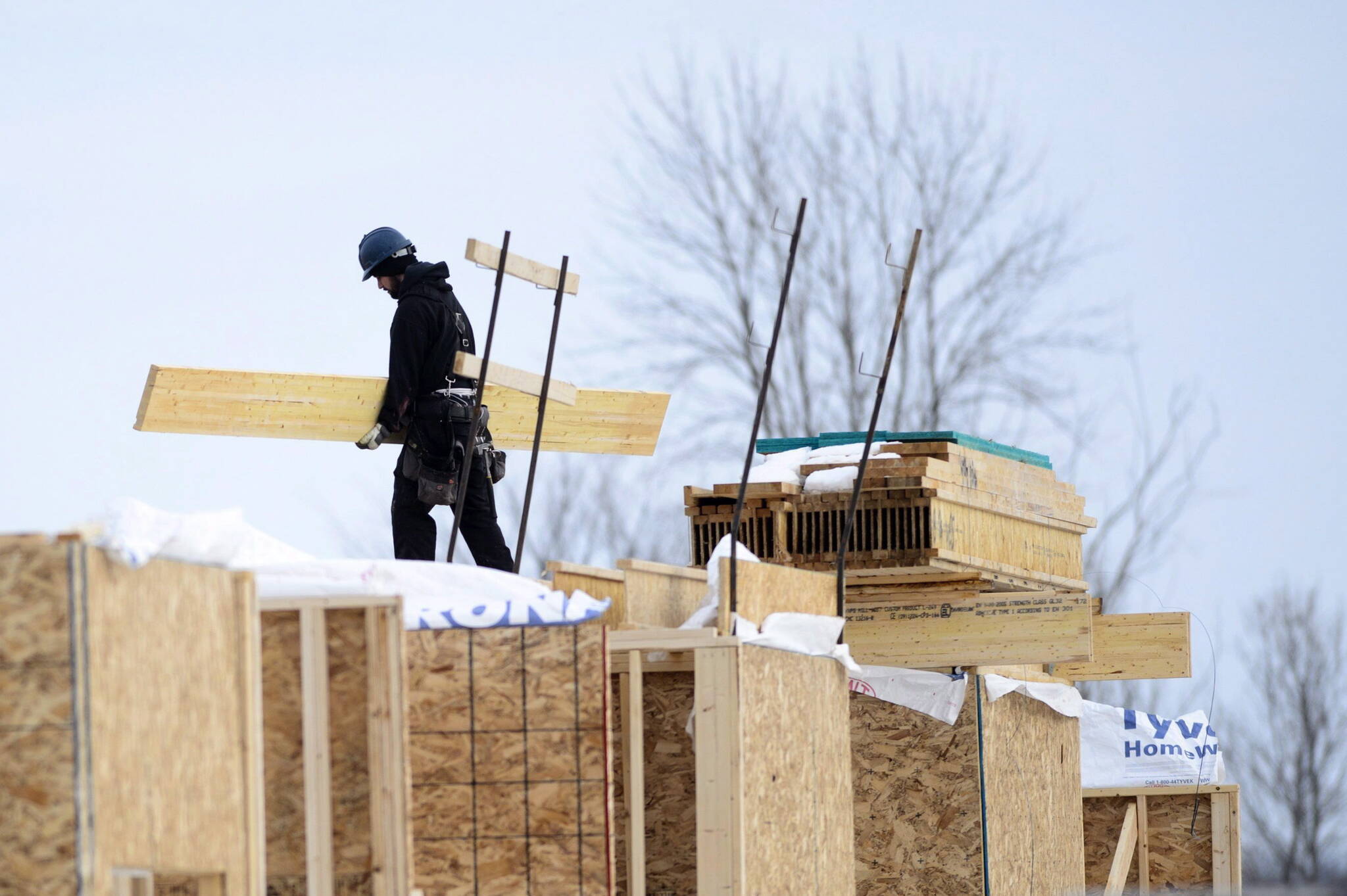 A worker carries wood as a house under construction is shown in a subdivision in Beckwith, Ont. THE CANADIAN PRESS/Sean Kilpatrick