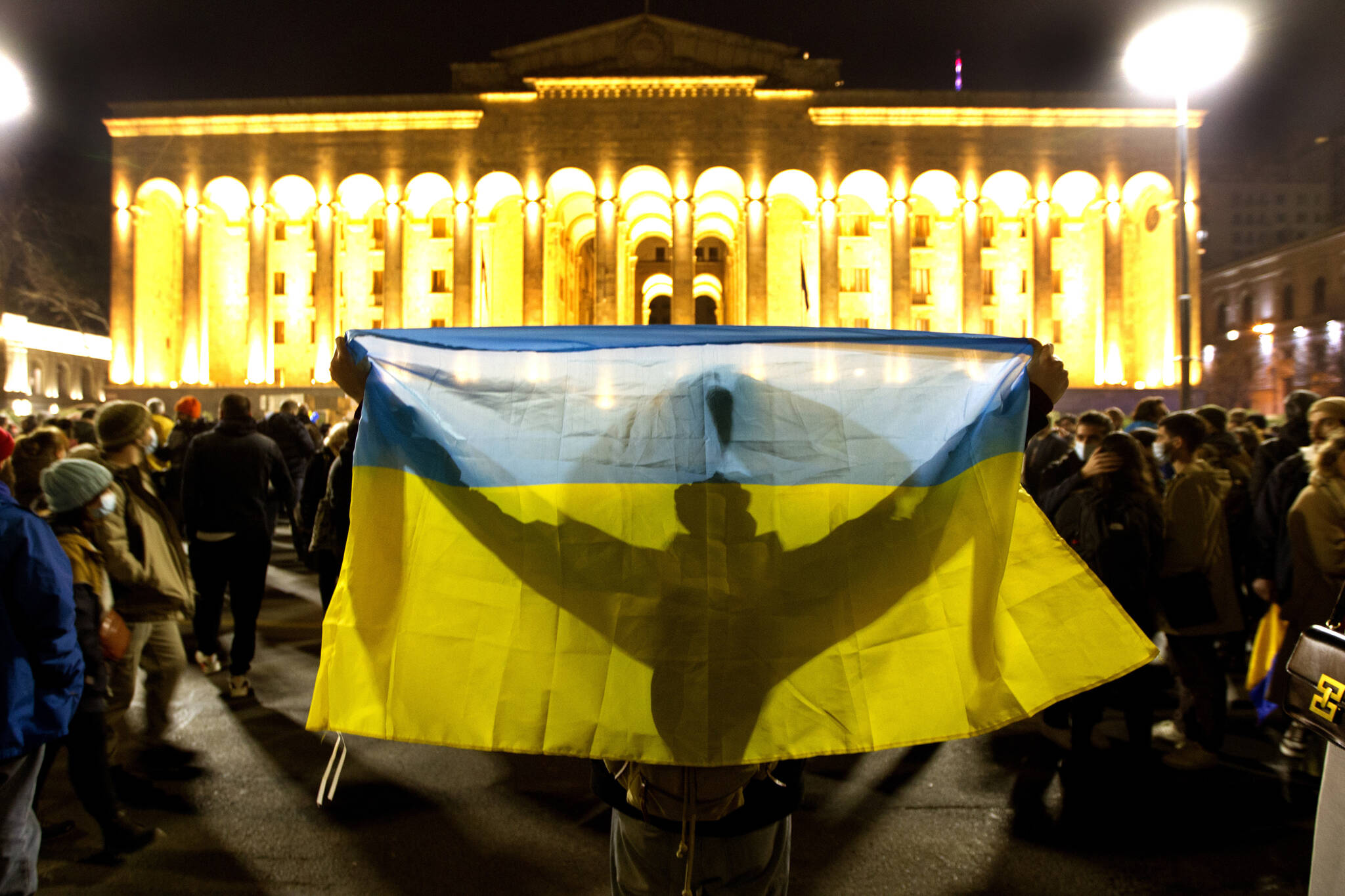 A demonstrator holds a Ukrainian national flag in front of the Georgian Parliament during an action against Russia’s attack on Ukraine in Tbilisi, Georgia, Tuesday, March 1, 2022. Russian shelling pounded civilian targets in Ukraine’s second-largest city again, and a 40-mile convoy of tanks and other vehicles threatened the capital. (AP Photo/Shakh Aivazov)