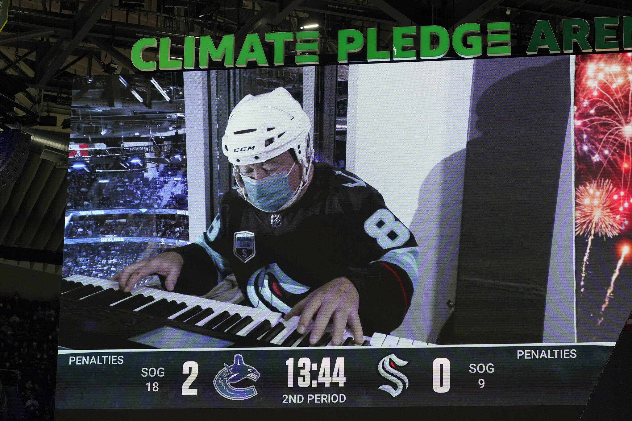 Rod Masters, who played the organist in the 1977 hockey movie “Slap Shot,” is shown on a video scoreboard as he plays during the second period of an NHL hockey game between the Seattle Kraken and the Vancouver Canucks, Saturday, Jan. 1, 2022, in Seattle. The Kraken announced recently that Masters will be the team’s new in-house organist. (AP Photo/Ted S. Warren)