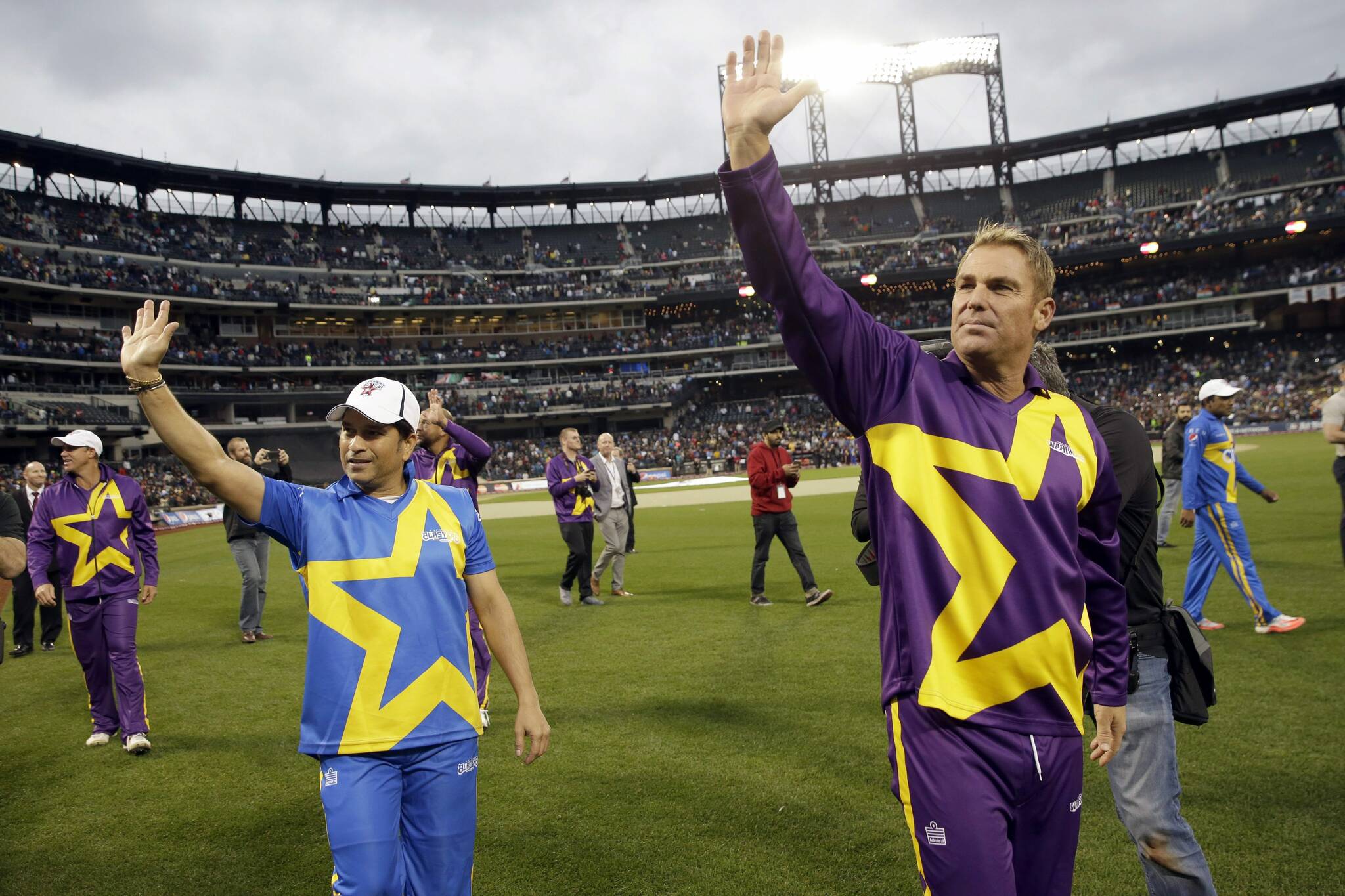 Shane Warne, right, waves at fans as he takes a lap around the field after the first game of the Cricket All-Stars series games, Saturday, Nov. 7, 2015, at Citi Field in New York. (AP Photo/Mary Altaffer)