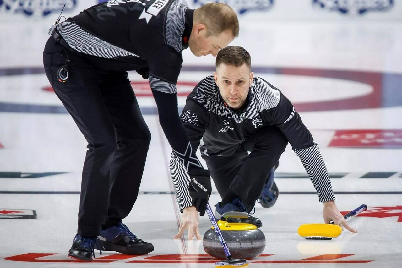 Team Wild Card One skip Brad Gushue, right, makes a shot as lead Geoff Walker sweeps while they play Team Quebec at the Tim Hortons Brier in Lethbridge, Alta., Saturday, March 5, 2022. THE CANADIAN PRESS/Jeff McIntosh