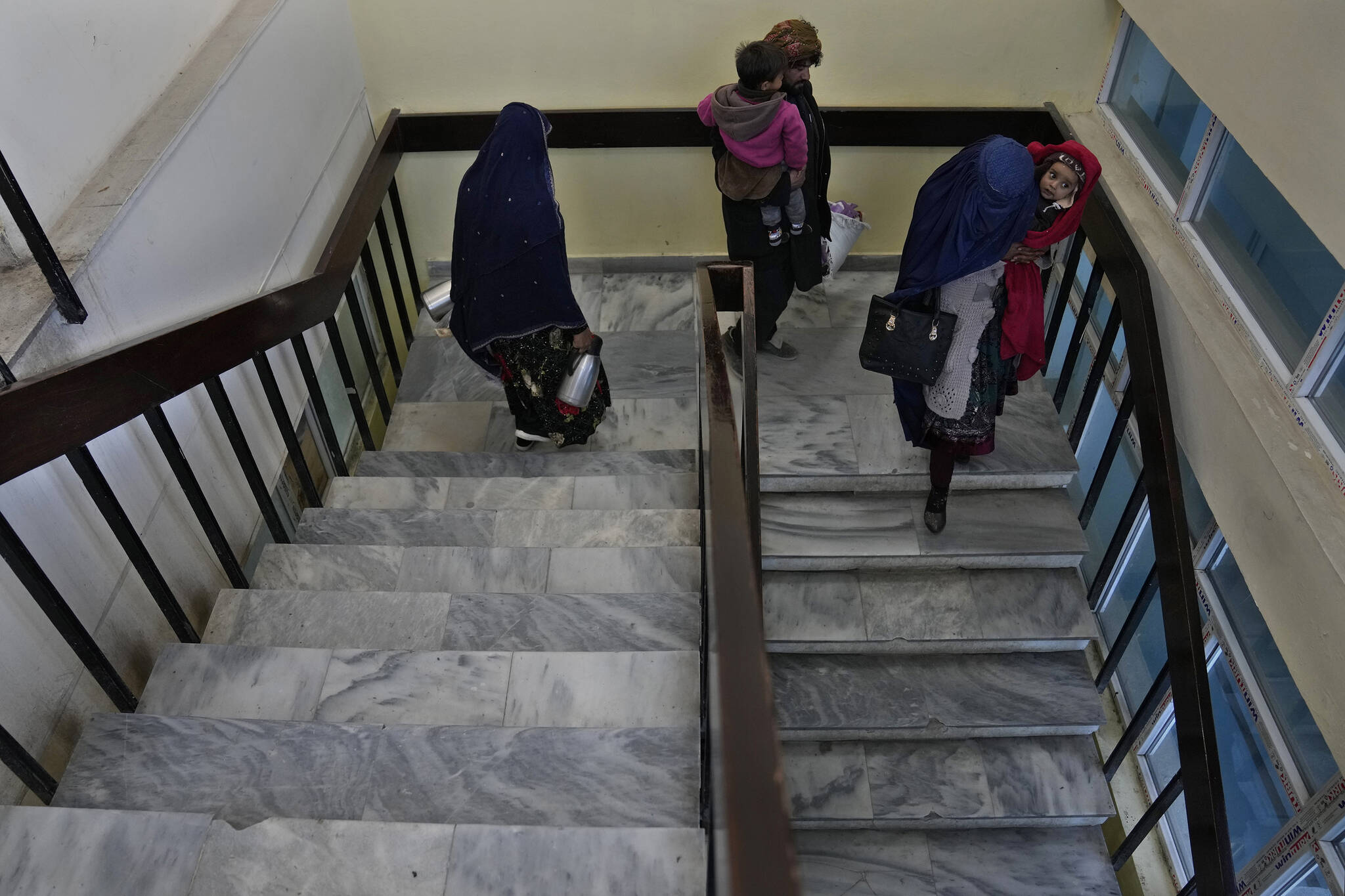 Afghan parents carry their children, as they leave the malnutrition ward floor, at the Indira Gandhi Children’s Hospital, in Kabul, Afghanistan, Thursday, Feb. 24, 2022. (AP Photo/Hussein Malla)