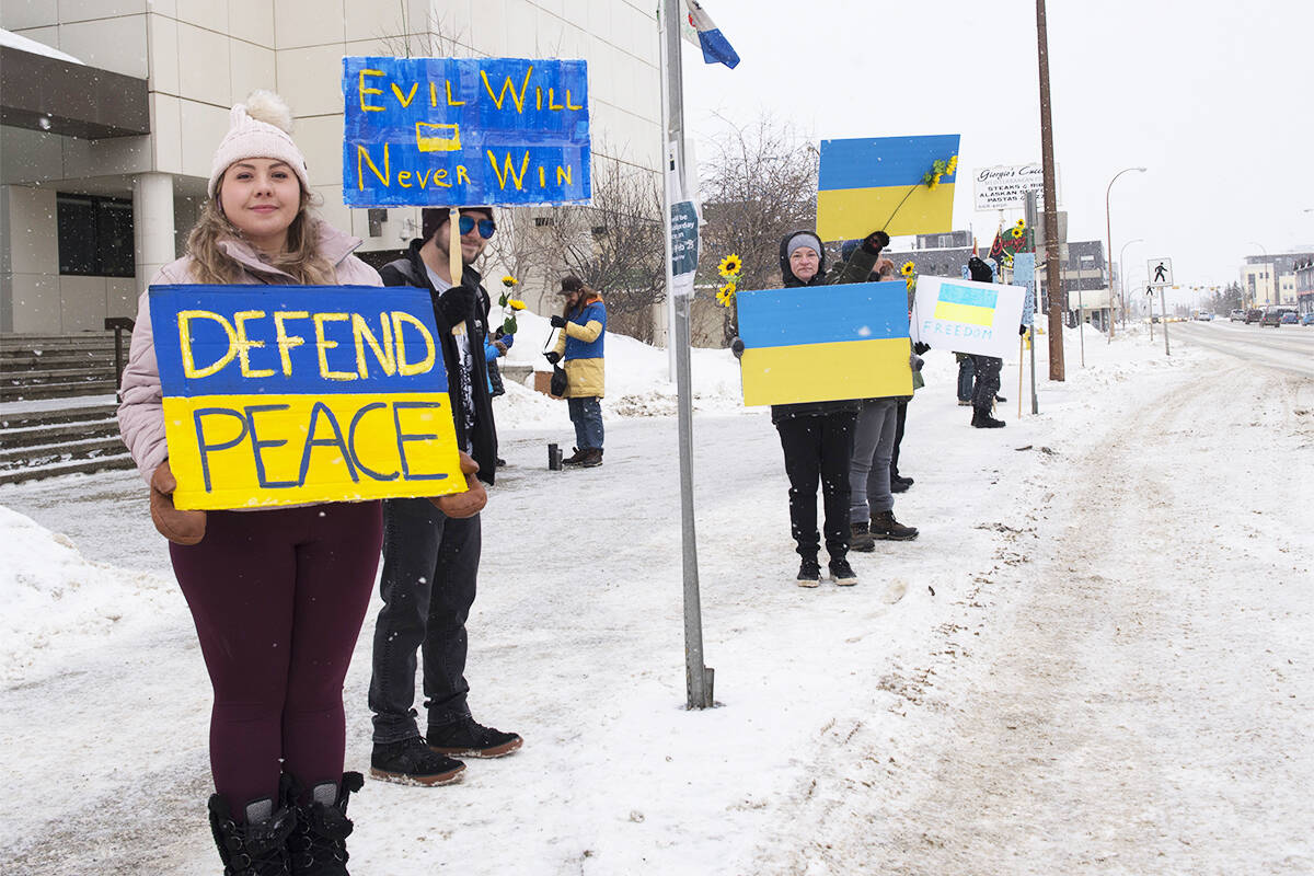 Tiara and Damian Topps stand with a small group who waved signs in support of Ukraine on the steps of the courthouse in Whitehorse on Feb. 26, 2022. A larger rally held in support of the Eastern European Nation that was invaded by Russia on Feb. 24 was held on Feb. 27. (Jim Elliot/Yukon News)