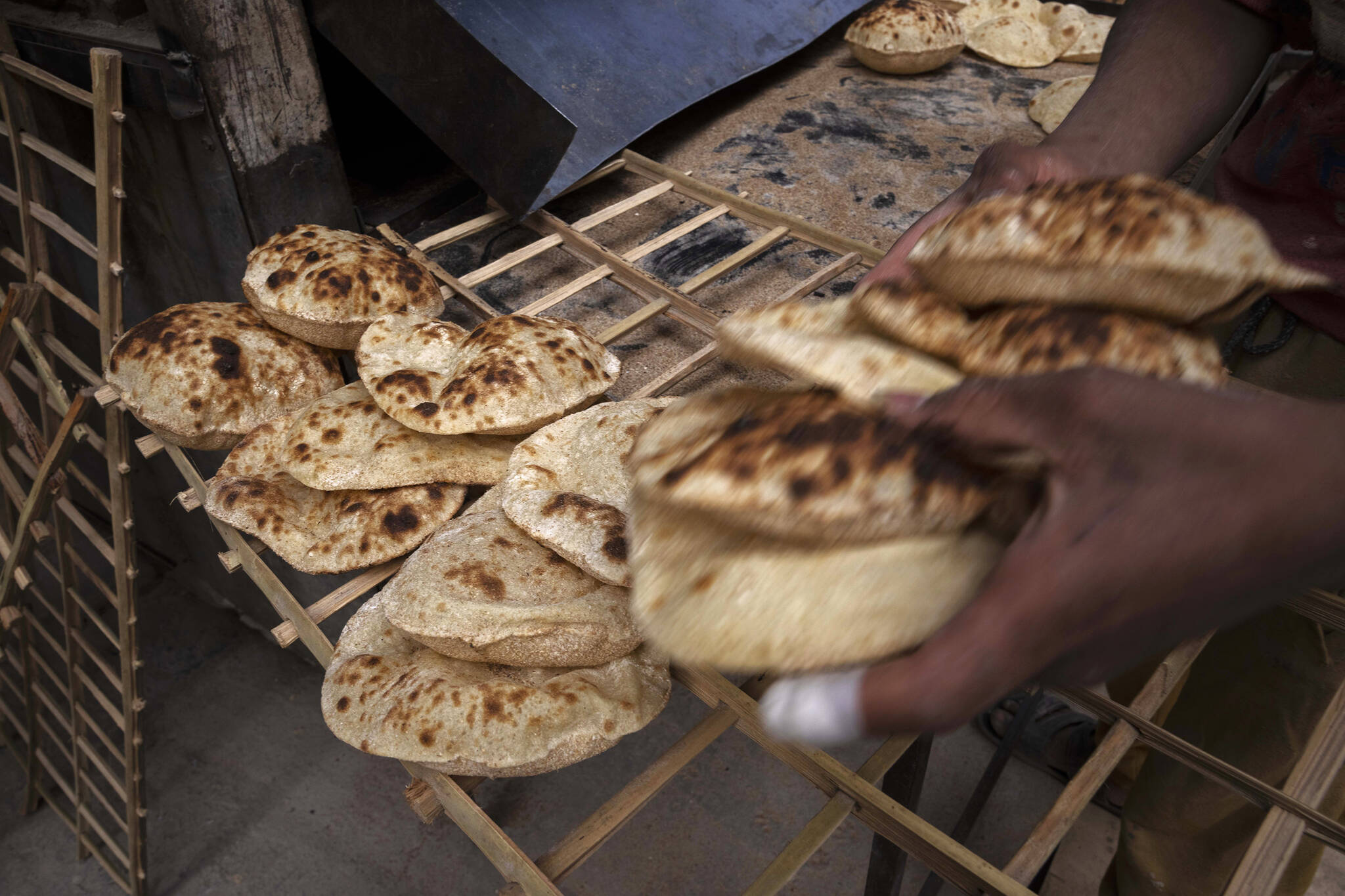 FILE - A worker collects Egyptian traditional ‘baladi’ flatbread, at a bakery, in el-Sharabia, Shubra district, Cairo, Egypt, Wednesday, March 2, 2022. Ukraine’s government banned the export of wheat, oats and other food staples on Wednesday, March 9, 2022 as authorities try to make sure they can feed people while Russia’s invasion intensifies.(AP Photo/Nariman El-Mofty, File)