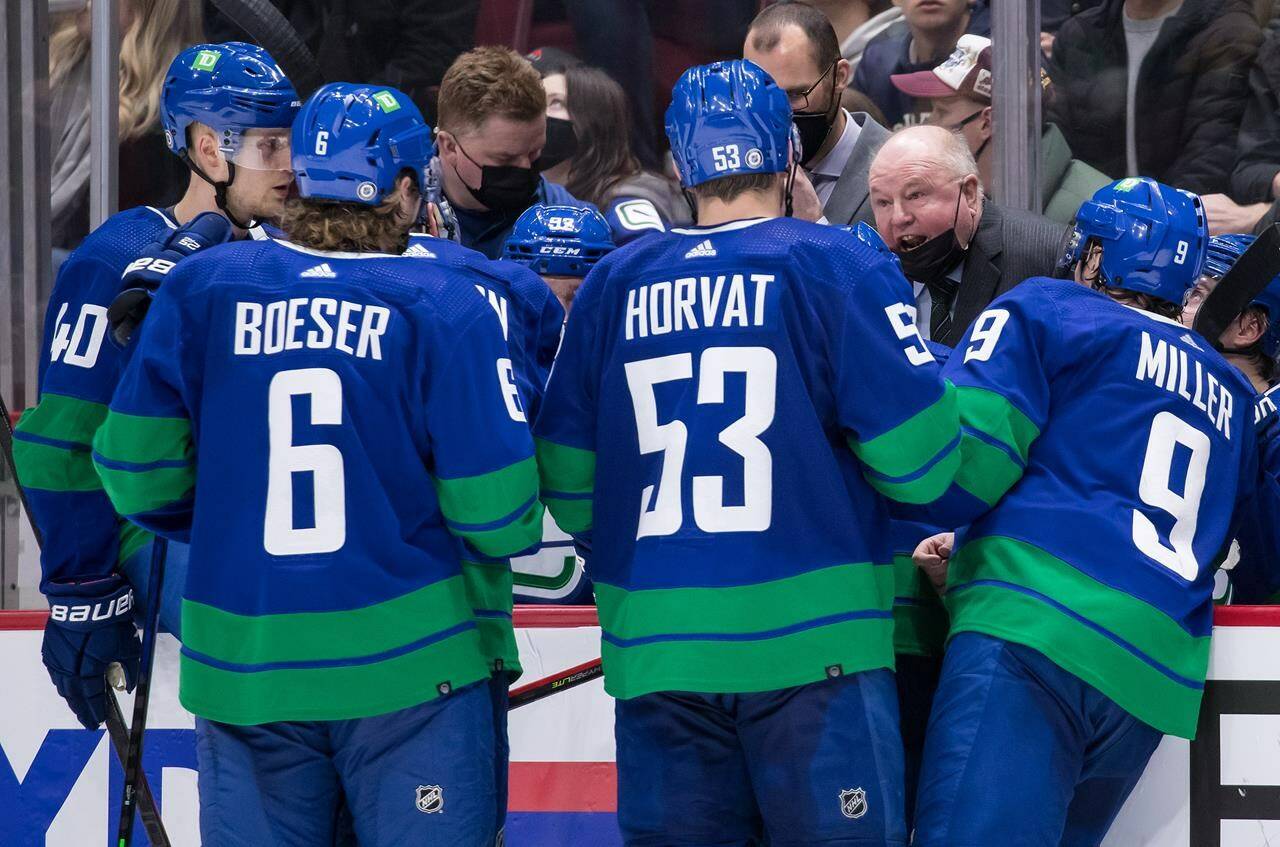 Vancouver Canucks head coach Bruce Boudreau, back right, talks to Elias Pettersson, from left to right, Brock Boeser, Bo Horvat and J.T. Miller during a timeout in the third period of an NHL hockey game against the Columbus Blue Jackets in Vancouver, on Dec. 14, 2021. THE CANADIAN PRESS/Darryl Dyck