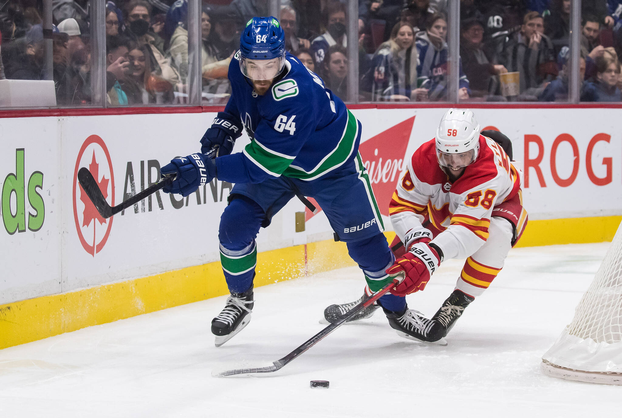 Calgary Flames’ Oliver Kylington, right, of Sweden, checks Vancouver Canucks’ Tyler Motte during the first period of an NHL hockey game in Vancouver, on Saturday, March 19, 2022. THE CANADIAN PRESS/Darryl Dyck