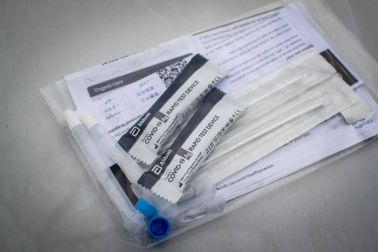 Two COVID-19 rapid tests that were given to a motorist are displayed at a Fraser Health drive-thru pick up site in Surrey, B.C., Thursday, Jan. 20, 2022. People in their 30s and older can now pick up packs of free COVID-19 tests at pharmacies across British Columbia. THE CANADIAN PRESS/Darryl Dyck