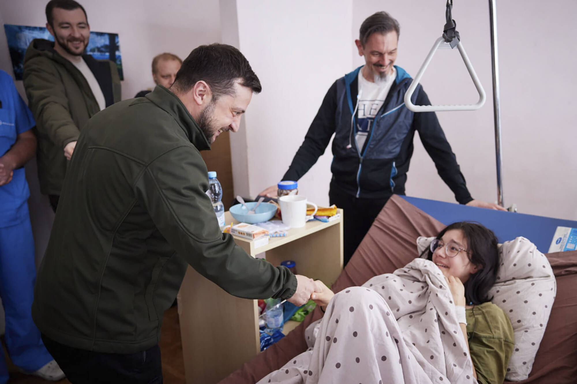 In this photo provided by the Ukrainian Presidential Press Office on Thursday, March 17, 2022, President Volodymyr Zelenskyy, shakes hands with a wounded Kateryna Vlasenko, 16, a refugee from Vorzel who covered her junior brother with her body during Russian shelling as they ran from their home town in a hospital in Kyiv, Ukraine. (Ukrainian Presidential Press Office via AP)