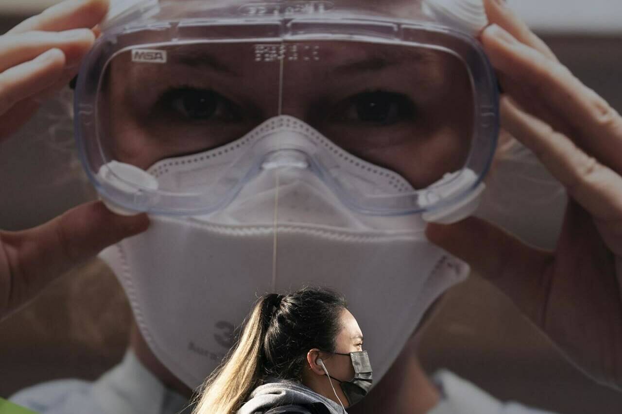 A woman wears a protective face mask to help prevent the spread of COVID-19 as she walks past a billboard from the Vancouver General Hospital in Vancouver Thursday, April 8, 2021. THE CANADIAN PRESS/Jonathan Hayward