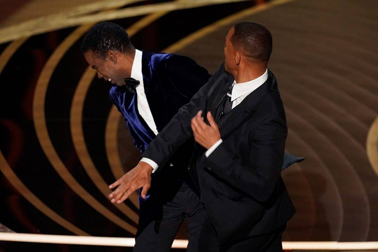 Will Smith, right, hits presenter Chris Rock on stage while presenting the award for best documentary feature at the Oscars on Sunday, March 27, 2022, at the Dolby Theatre in Los Angeles. THE CANADIAN PRESS/AP-Chris Pizzello