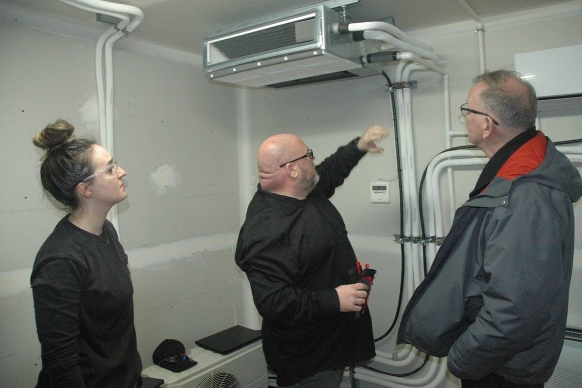Bruce Ralston, BC’s Minister of Energy, Mines and Low Carbon Innovation (right), talks heat pumps with Deon Lane (centre), an instructor at VIU's refrigeration air-conditioning mechanic shop located in the university's Cowichan Trades Centre, and student Taylor Bacon. (Robert Barron/Citizen)