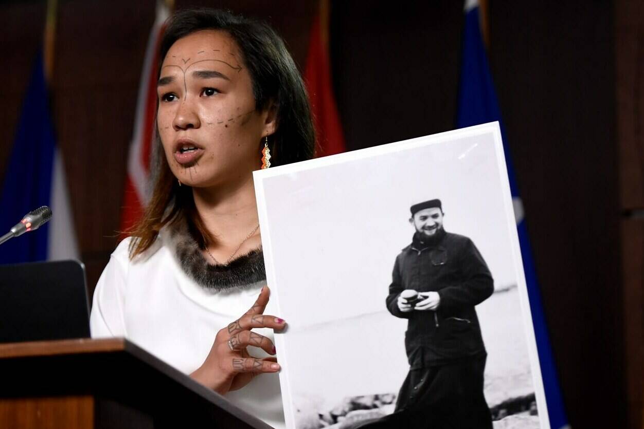 NDP MP Mumilaaq Qaqqaq holds a photo of Fr. Johannes Rivoire, who is wanted in Canada for abusing children in Nunavut but now resides in France, during a news conference calling on Minister of Justice David Lametti to investigate crimes against Indigenous people in Canada at residential schools, on Parliament Hill in Ottawa, on Thursday, July 8, 2021. THE CANADIAN PRESS/Justin Tang