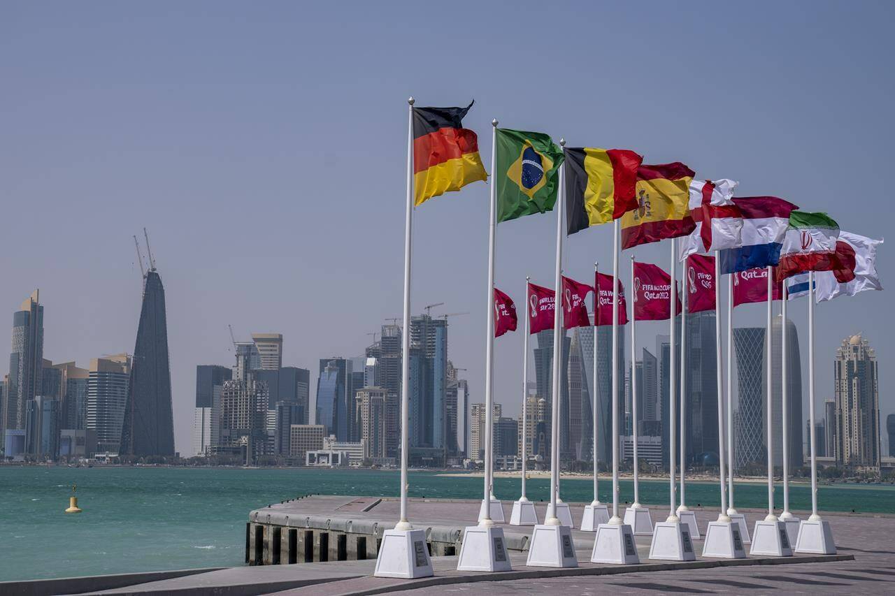 Flags of some of the qualified countries of the World Cup wave at the seafront in Doha, Qatar, Tuesday, March 29, 2022. The draw for the World Cup will be held in Doha on April 1.(AP Photo/Darko Bandic)