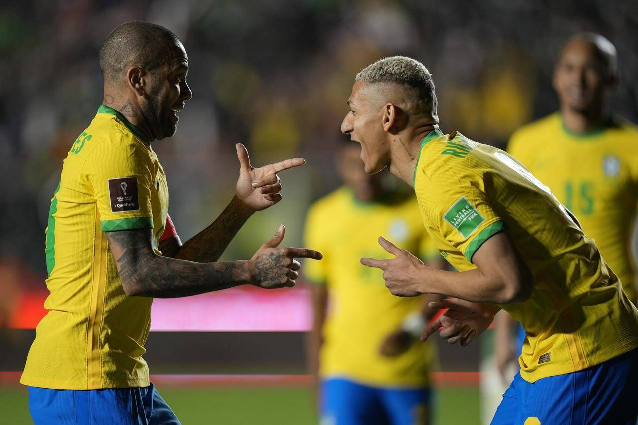 Brazil’s Richarlison, right, celebrates with teammate Dani Alves after scoring his side’s fourth goal against Bolivia during a qualifying soccer match for the FIFA World Cup Qatar 2022 in La Paz, Bolivia, Tuesday, March 29, 2022. (AP Photo/Juan Karita)