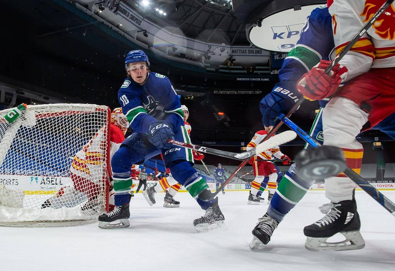 Vancouver Canucks’ Jake Virtanen (18) and Calgary Flames’ Josh Leivo, front right, vie for the puck as goalie Jacob Markstrom, back left, of Sweden, watches during the first period of an NHL hockey game in Vancouver, on Saturday, February 13, 2021. A trial date has been set for a former Vancouver Canucks forward charged with sexual assault.THE CANADIAN PRESS/Darryl Dyck