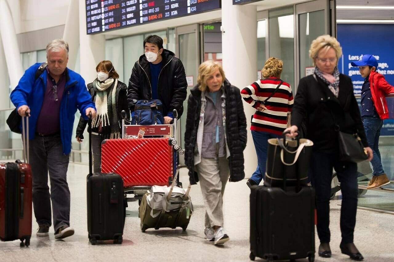 People wear masks as a precaution due to the coronavirus outbreak as they arrive at the International terminal at Toronto Pearson International Airport in Toronto on Saturday, January 25, 2020. As of tomorrow, vaccinated travellers will no longer need a COVID-19 test to enter Canada. THE CANADIAN PRESS/Nathan Denette
