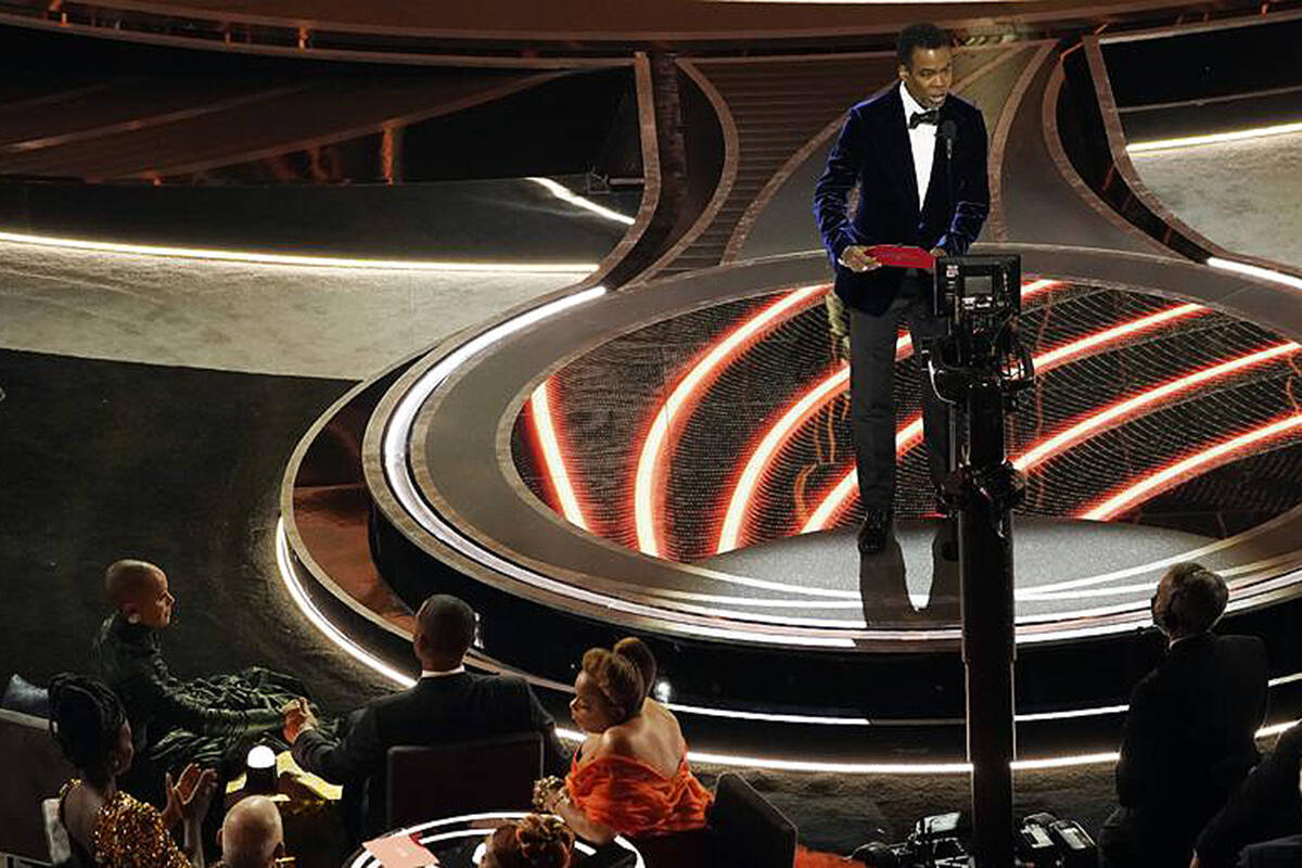 Presenter Chris Rock, right, speaks onstage as Jada Pinkett Smith and Will Smith, bottom left, look on after Smith went onstage and slapped Rock at the Oscars, Sunday, March 27, 2022, at the Dolby Theatre in Los Angeles. (AP Photo/Chris Pizzello)