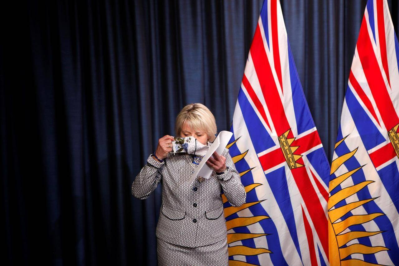 Provincial health officer, Dr. Bonnie Henry, puts on her protective mask after releasing details about a COVID-19 vaccination card that will be needed by anyone wanting to eat in restaurants, visit theatres or go to other events. She made the announcement at a news conference at the B.C. legislature in Victoria on Monday, Aug. 23, 2021. THE CANADIAN PRESS/Chad Hipolito