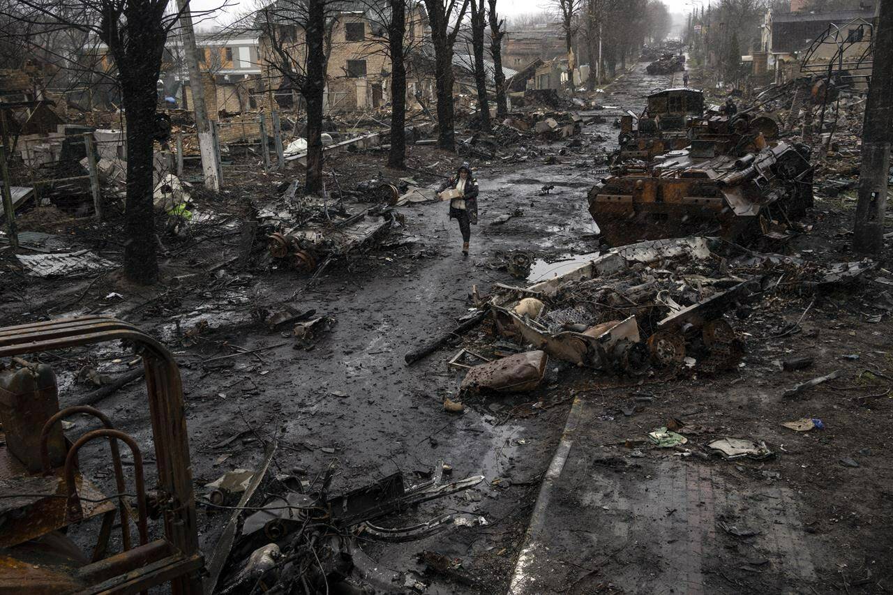 A woman walks amid destroyed Russian tanks in Bucha, in the outskirts of Kyiv, Ukraine, Sunday, April 3, 2022. (AP Photo/Rodrigo Abd)