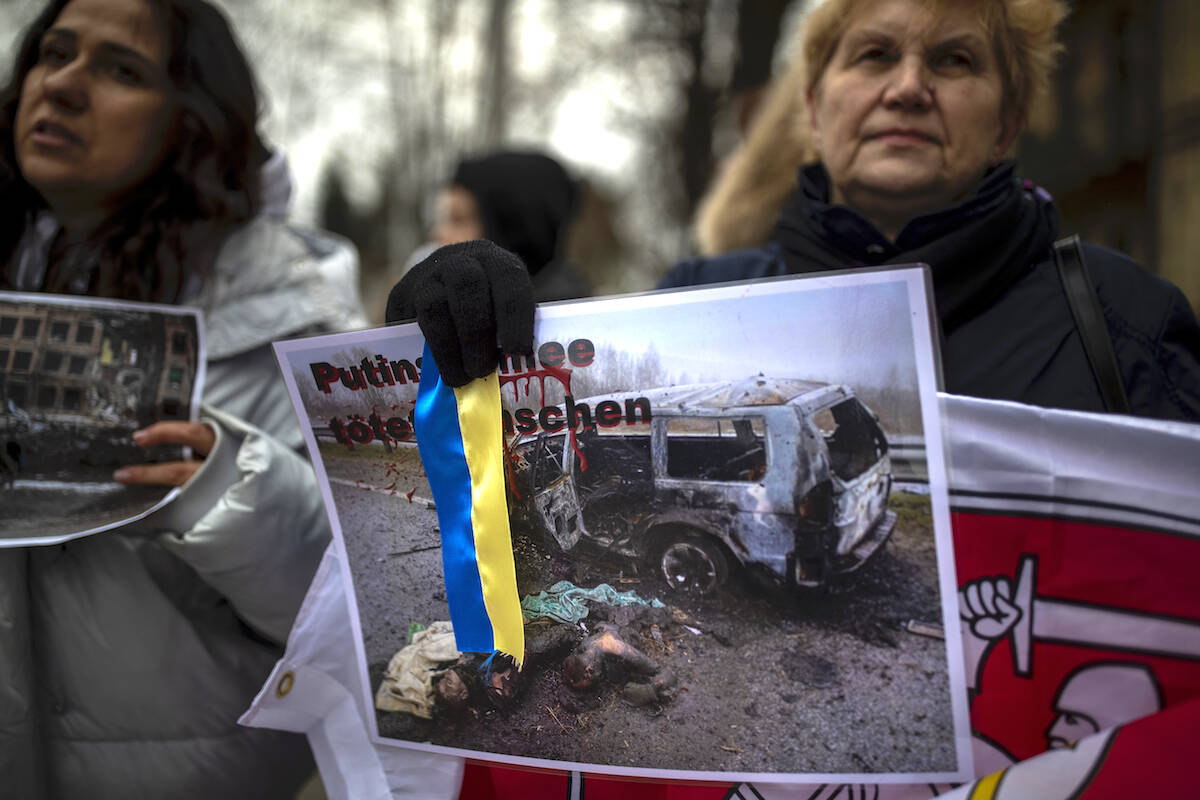 People take part in a protest against the Russian invasion of Ukraine in front of the German embassy in Vilnius, Lithuania, Monday, April 4, 2022. Russia is facing a fresh wave of condemnation after evidence emerged of what appeared to be deliberate killings of civilians in Ukraine. (AP Photo/Mindaugas Kulbis)