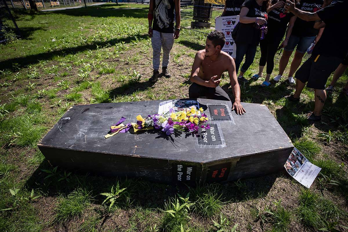 A man pauses at a coffin after carrying it during a memorial march to remember victims of overdose deaths in Vancouver on Saturday, August 15, 2020. April 14, 2022 marks six years since B.C. declared a public health emergency around the opioid crisis. THE CANADIAN PRESS/Darryl Dyck