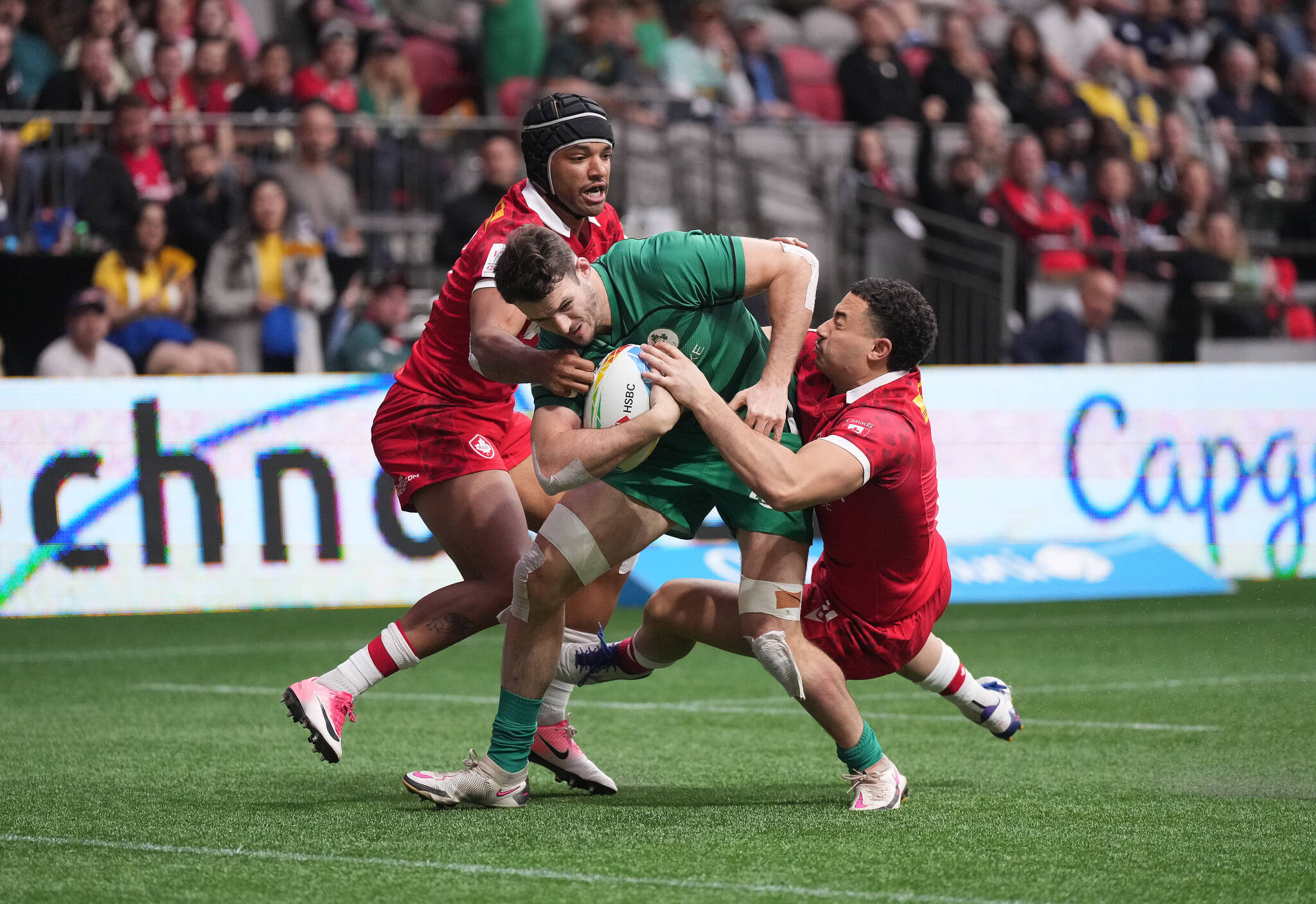 Ireland’s Jack Kelly, centre, fights off Canada’s Anton Ngongo, left, and Elias Ergas, right, to score a try during HSBC Canada Sevens rugby action, in Vancouver, B.C., Sunday, April 17, 2022. THE CANADIAN PRESS/Darryl Dyck