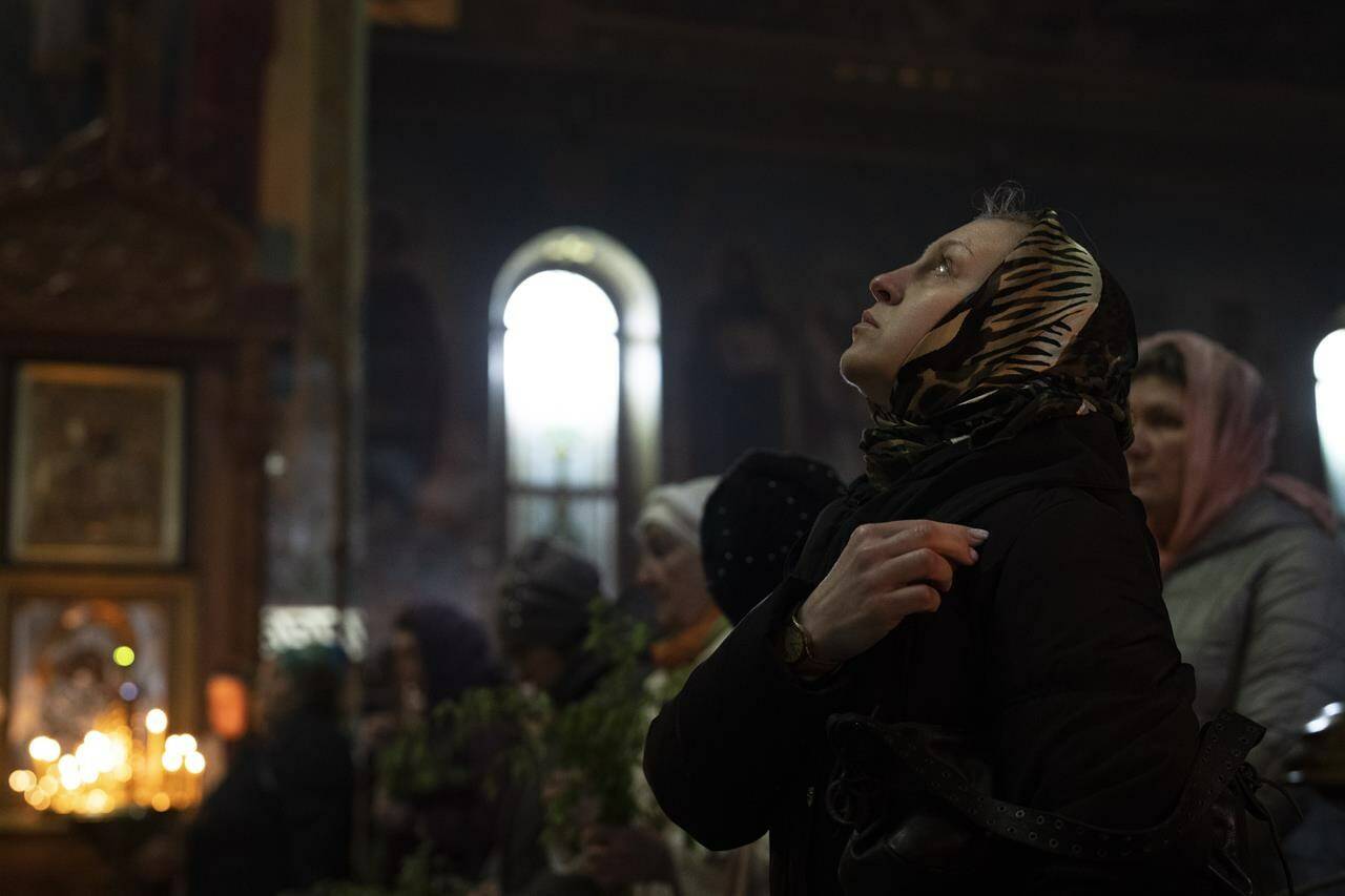 A woman makes the sign of cross as she participates in an Orthodox service celebrating Palm Sunday, in the Holy Trinity Cathedral, in Kramatorsk, Ukraine, Sunday, April 17, 2022. (AP Photo/Petros Giannakouris)