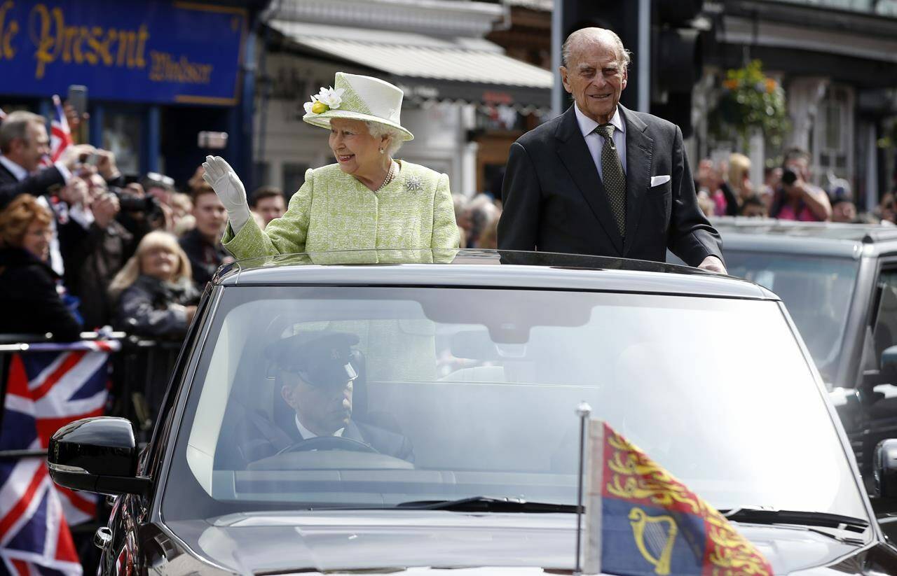 FILE - Britain’s Queen Elizabeth II greets the crowds as she rides with Prince Phillip in an open top car to celebrates her 90th birthday in Windsor, England, Thursday, April, 21, 2016. Queen Elizabeth II is marking her 96th birthday privately on Thursday, April 21, 2022 retreating to the Sandringham estate in eastern England that has offered the monarch and her late husband, Prince Philip, a refuge from the affairs of state. (AP Photo/Alastair Grant, File)