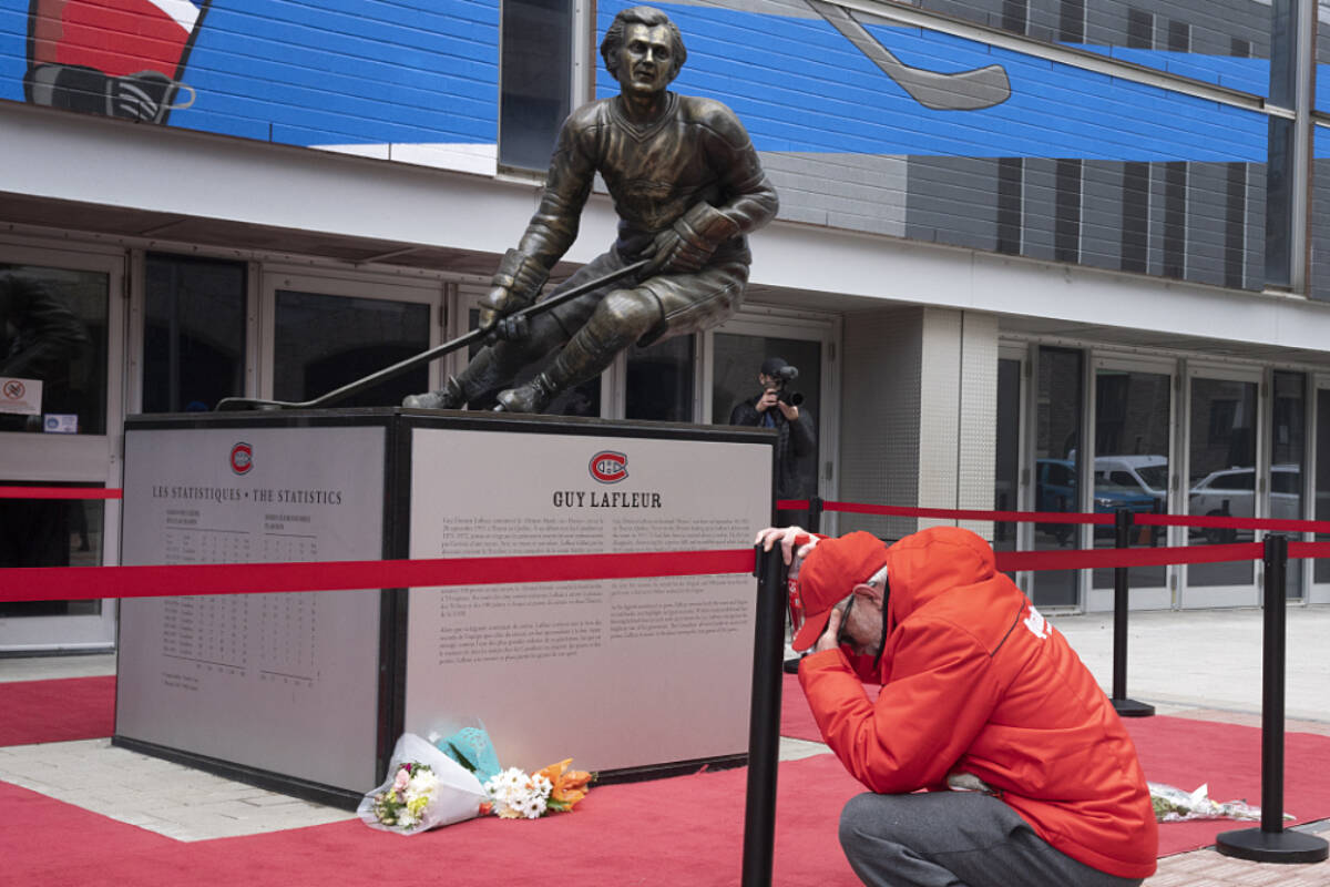 A fan pays his respects in front of a bronze statue of Canadiens legend Guy Lafleur, Friday, April 22, 2022, in Montreal. Hockey Hall of Famer Guy Lafleur, who helped the Montreal Canadiens win five Stanley Cup titles in the 1970s, has died at age 70. (Ryan Remiorz/The Canadian Press via AP)