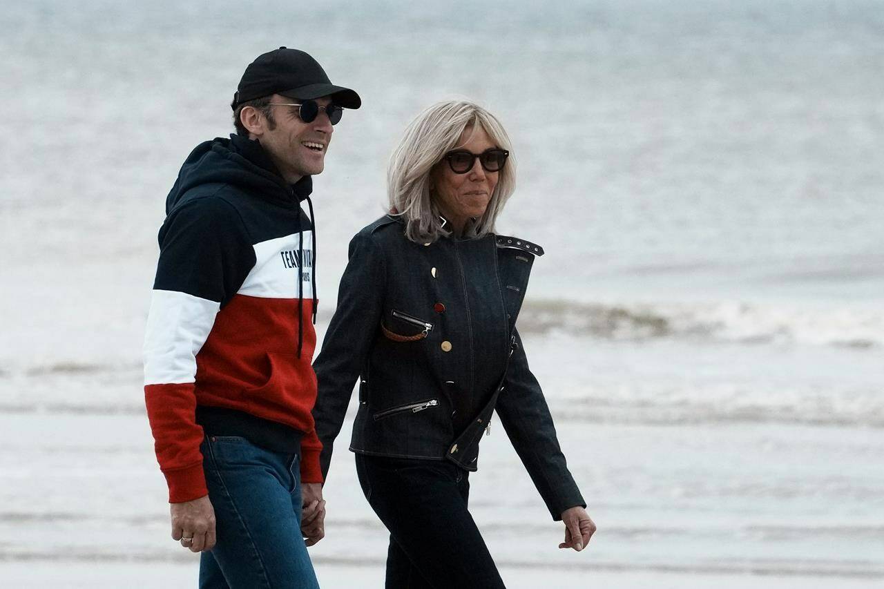 Centrist candidate and French President Emmanuel Macron, left, and his wife Brigitte Macron walk on the beach in Le Touquet, northern France, Saturday, April 23, 2022. French President Emmanuel Macron is in pole position to win reelection Sunday, April 24, 2022 in France's presidential runoff. (AP Photo/Thibault Camus)