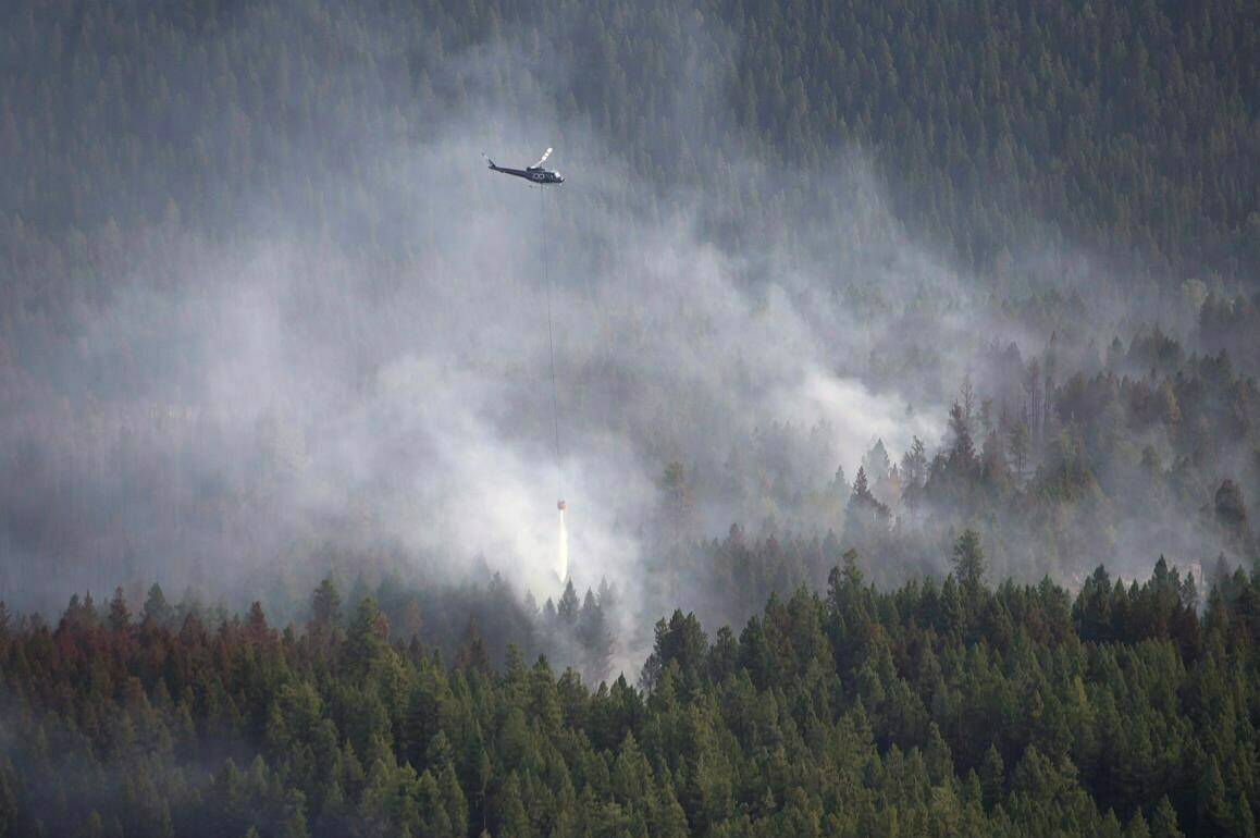 A helicopter dumps water on a fire outside Kelowna, B.C., on Monday, Aug. 28, 2017. Wildfires in Canadian and Alaskan boreal forests release large quantities of greenhouse gases that exacerbate climate change, a new study says. THE CANADIAN PRESS/Jonathan Hayward