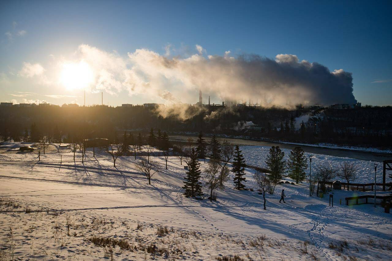 A man walks in frigid weather at Rundle Park as emissions rise from the Imperial Oil Strathcona Refinery, in Edmonton, Wednesday, Dec. 25, 2019. The federal government is pushing legislation to enshrine the right to a healthy environment into law but is giving itself up to two more years to define what that means. THE CANADIAN PRESS/Darryl Dyck