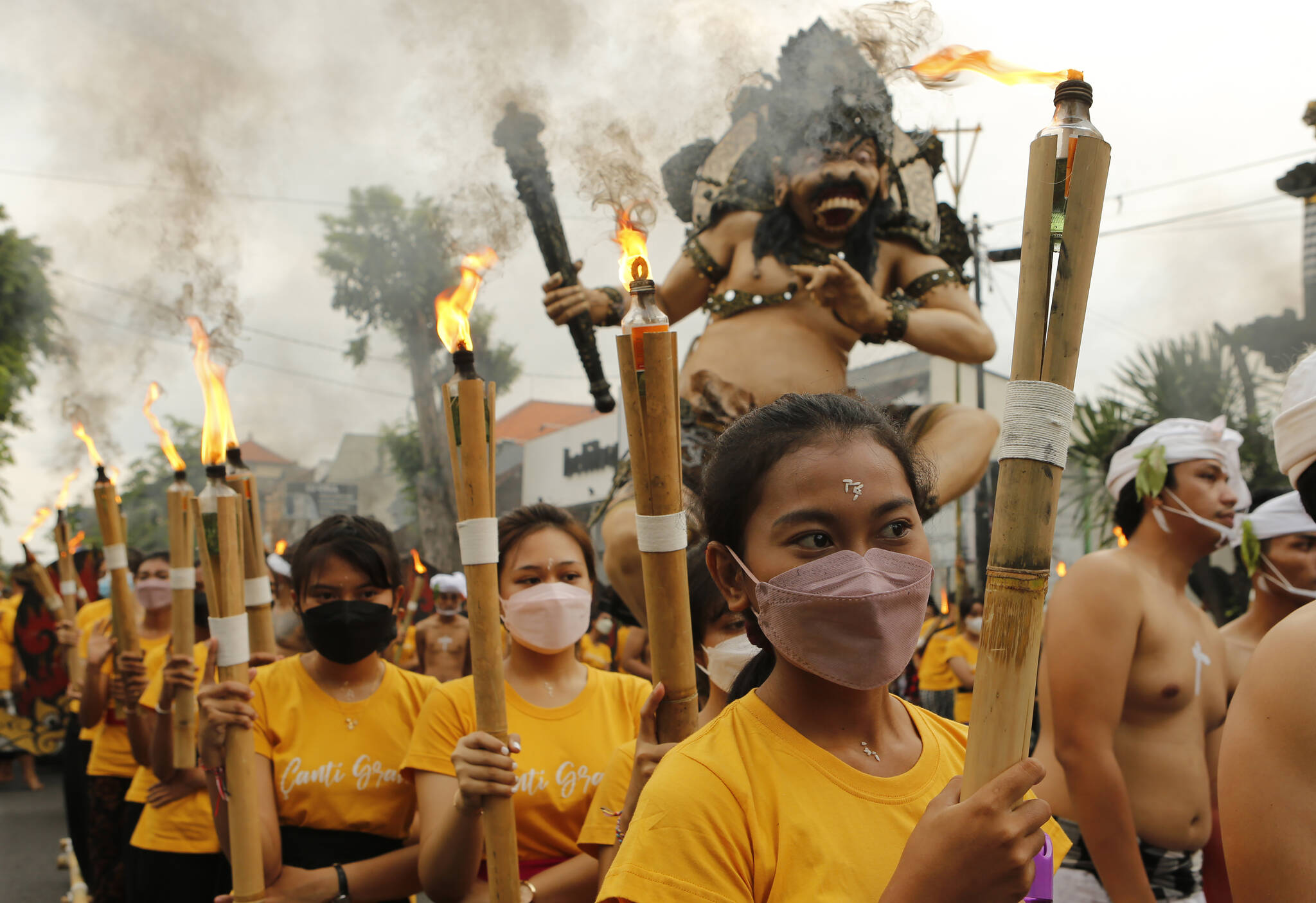 Women carrying torches line up in front of a giant effigy locally known as “ogoh-ogoh” that represents evil spirits during Nyepi celebration, the annual day of silence marking Balinese Hindu new year in Bali, Indonesia on Wednesday, March 2, 2022. (AP Photo/Firdia Lisnawati)