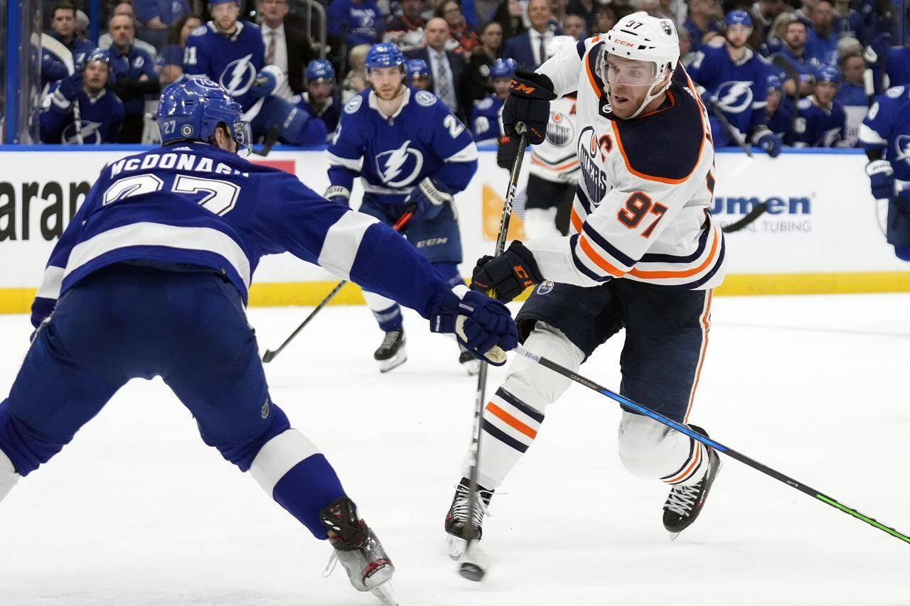 Edmonton Oilers centre Connor McDavid (97) fires the puck past Tampa Bay Lightning defenceman Ryan McDonagh (27) and goaltender Andrei Vasilevskiy (not shown) for a goal during the third period of an NHL hockey game Wednesday, Feb. 23, 2022, in Tampa, Fla. (AP Photo/Chris O’Meara)