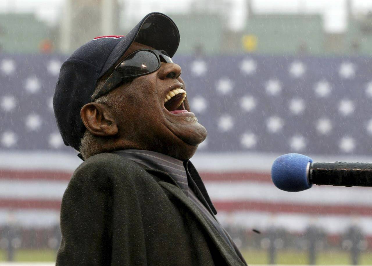 Ray Charles sings “America The Beautiful,” in the rain at Fenway Park in Boston, April 11, 2003. Charles will be posthumously inducted into the Country Music Hall of Fame on Sunday, May 1, 2022, in Nashville, Tenn., along with The Judds. The ceremony will continue despite the death Saturday of Naomi Judd, who performed with daughter Wynonna as The Judds. (AP Photo/Winslow Townson, File)