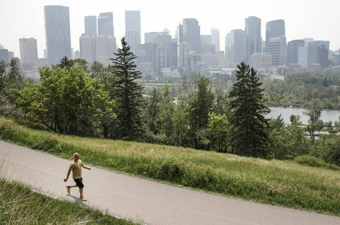 A haze of wildfire smoke from B.C. hangs over the downtown as pedestrian walks past in Calgary, Alta., Thursday, July 15, 2021. The record-breaking heat wave that scorched western North America in June 2021 was among the most extreme ever recorded globally, new modelling and analysis by researchers at universities in the United Kingdom shows. THE CANADIAN PRESS/Jeff McIntosh