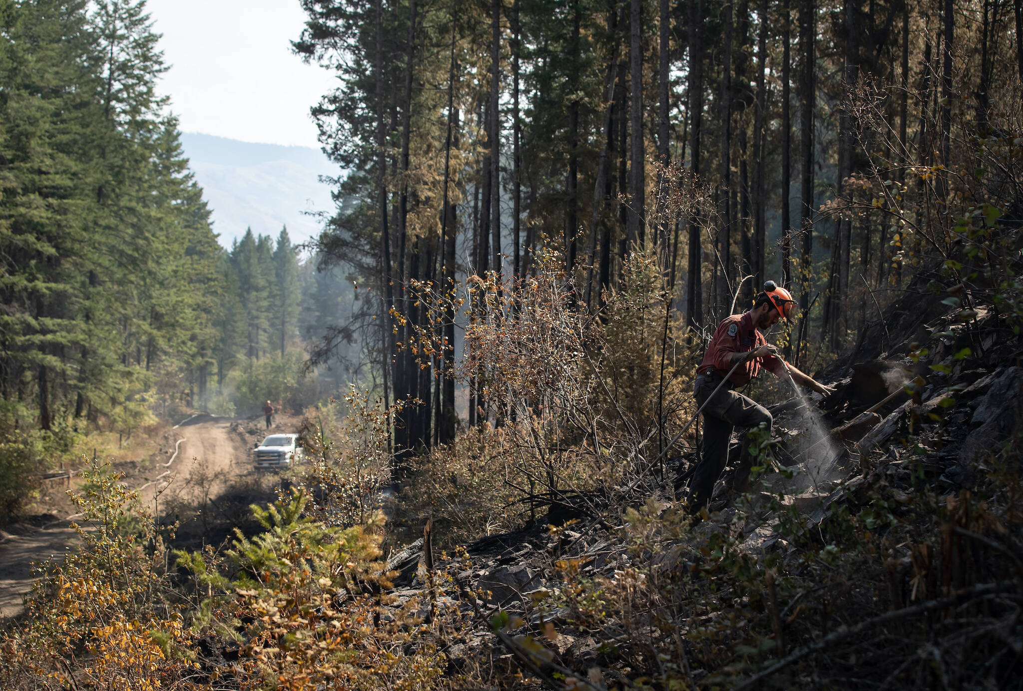 FILE – Wildland firefighter Ty Feldinger works on steep terrain to put out hot spots remaining from a controlled burn the B.C. Wildfire Service conducted to help contain the White Rock Lake wildfire on Okanagan Indian Band land, northwest of Vernon, B.C., on Wednesday, August 25, 2021. THE CANADIAN PRESS/Darryl Dyck
