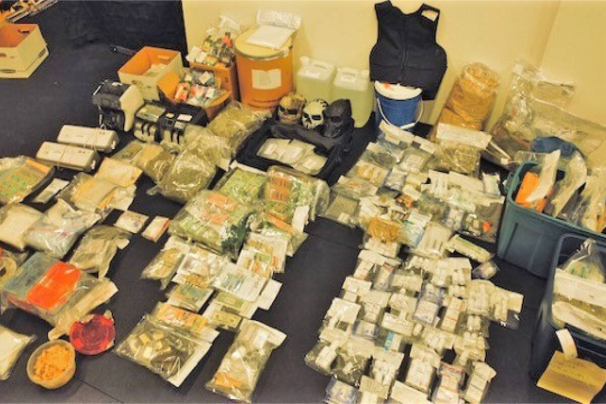 Packages of drugs and cash, money counters, body armour and skull-like face masks displayed across the floor (BC RCMP photo)