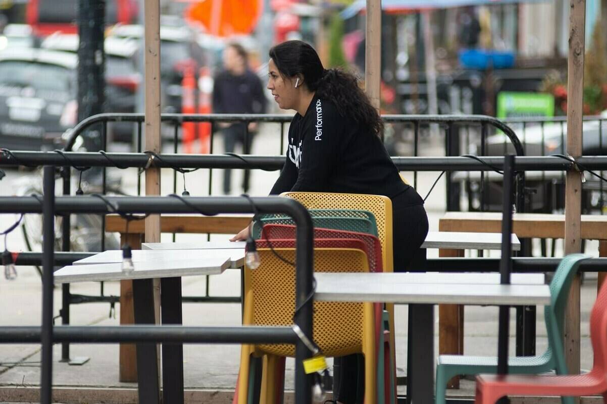 A worker organizes chairs and tables on the patio of a restaurant on College St., Toronto, Thursday, October 28, 2021. Restaurants across Canada are cutting back hours and tightening up menus as persistent labour shortages and spiking costs threaten to derail the industry’s comeback from crushing pandemic restrictions.THE CANADIAN PRESS/Eduardo Lima